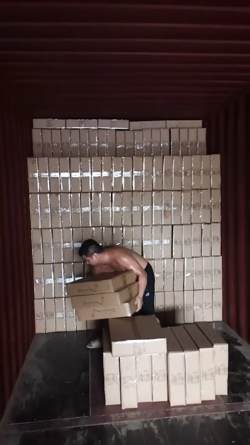 A wall of packed cartons stacked to the container ceiling, a loader carrying the next row